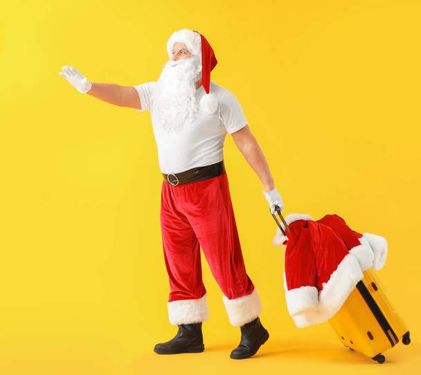 Санта-Клаус с багажом на цветном фоне. Концепция отпуска
 - Фото, изображение