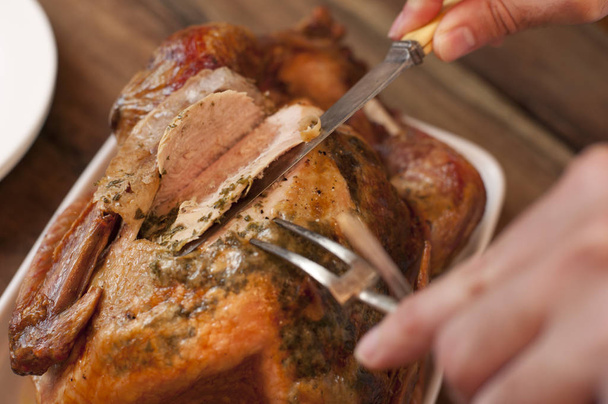 Closeup view from above of a man carving a tasty Thanksgiving roast turkey slicing the breast with a carving knife - Photo, image