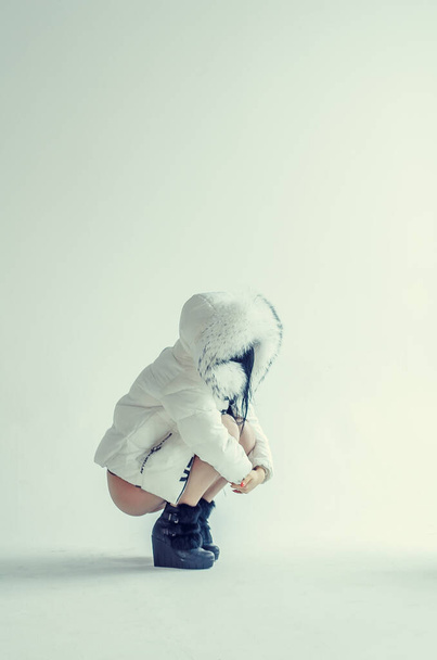 fiatal nő fehér kabát és fehérnemű pózol fehér háttér fényes fény. - Fotó, kép