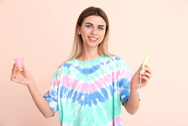 Young woman with menstrual cup and tampon on color background - Photo, Image