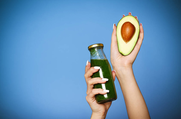 Close up of young girl holding avocado and green smoothie - Photo, Image