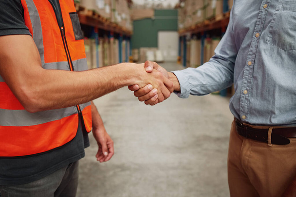 Close-up of photo of a handshake in formal clothing and uniform in warehouse  - Fotó, kép