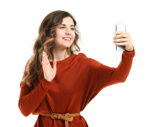 schöne junge Frau im warmen Pullover macht Selfie auf weißem Hintergrund - Foto, Bild