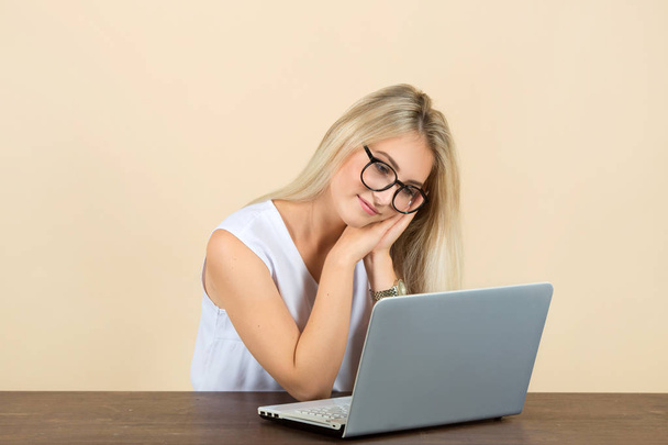 beautiful young woman in glasses on a beige background with a laptop - Zdjęcie, obraz