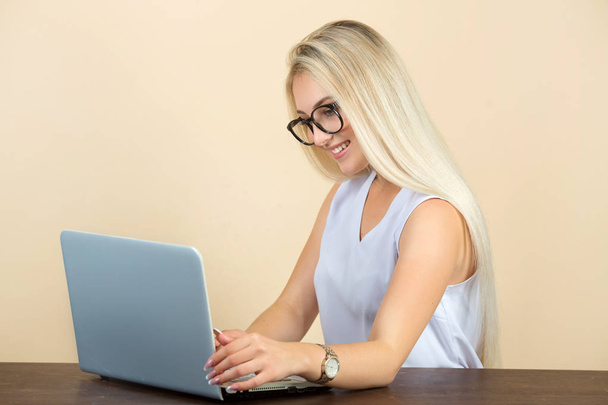 beautiful young woman in glasses on a beige background with a laptop - Fotografie, Obrázek