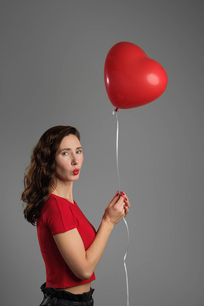 mooi emotioneel brunette meisje met rood ballon - Foto, afbeelding