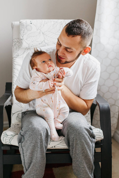 Caucasian father sitting in armchair with newborn baby girl boy. - Photo, Image