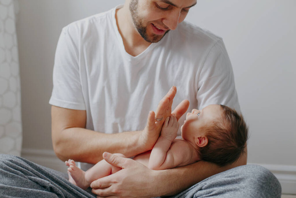 Onnellinen valkoihoinen isä pitelee vastasyntynyttä vauvaa polvillaan. Mies p
 - Valokuva, kuva