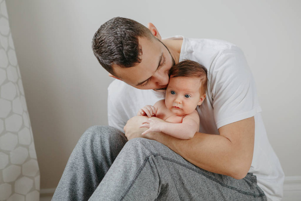 Onnellinen valkoihoinen isä pitelee vastasyntynyttä vauvaa polvillaan. Mies p
 - Valokuva, kuva