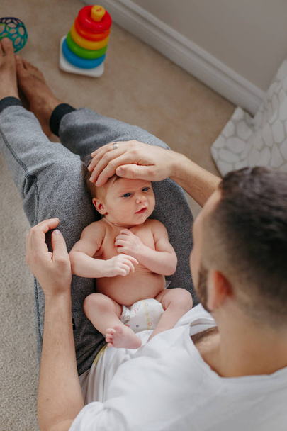 Šťastný bělošský otec držící novorozeně na kolenou. Man p - Fotografie, Obrázek