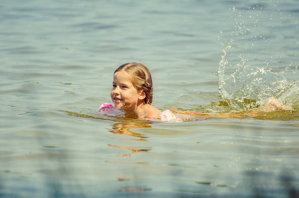 little girl learning how to swim in the lake  - 写真・画像