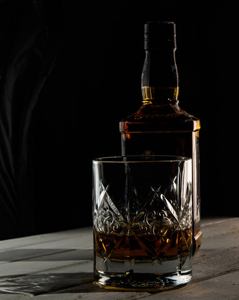 Bottle and glass of whiskey jn the dark background - Valokuva, kuva