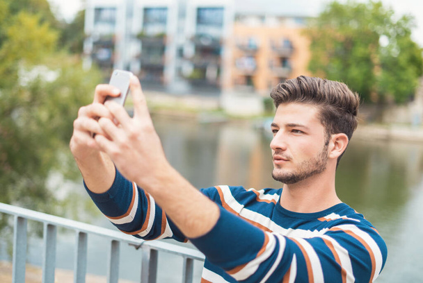Sharing happy selfie. Beautiful smiling man in casual wear taking selfie using his smart phone - Foto, Bild
