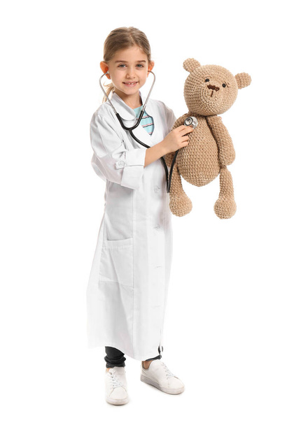 Cute little doctor with toy on white background - Foto, Imagen