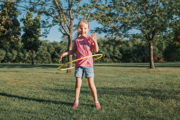 Cute smiling Caucasian preschool girl playing with hoola hoop in - 写真・画像