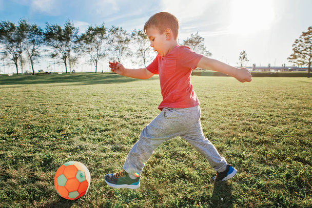 Маленький дошкільний кавказький хлопчик грає у футбол на плейгері. - Фото, зображення