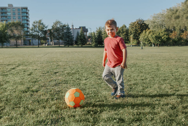 Little preschool Caucasian boy playing soccer football on playgr - Photo, Image