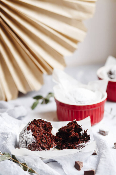 赤いカップにチョコレートマフィン.灰色と白の背景に茶色のケーキと小さな釉薬セラミックラメキン. - 写真・画像
