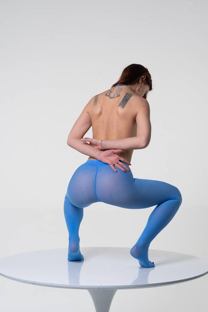 young beautiful girl pose in studio, stands in blue tights on the table - Foto, Imagen