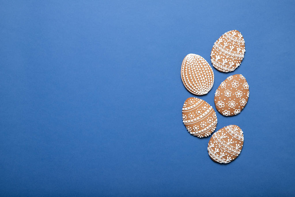 Easter cookies on a plate on a blue background. Place for text. Easter eggs. - Fotó, kép