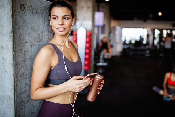 Young fit woman using smartphone at gym after exercise - Fotografie, Obrázek
