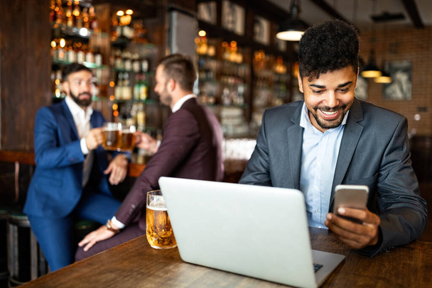 Business people drink beer after work. Businessmen enjoy a beer at a pub - Фото, зображення