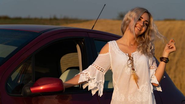 Kaunis seksikäs blondi nainen, punainen auto, kenttä
 - Valokuva, kuva