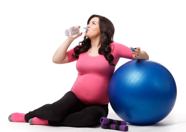 The active pregnant woman with gymnastic ball on a white background. Care of health and pregnancy. - Foto, afbeelding