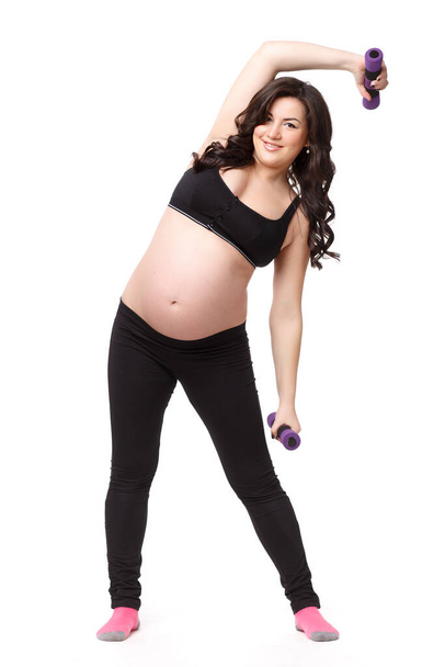 The active pregnant woman with dumbbells on a white background. Care of health and pregnancy. - Φωτογραφία, εικόνα
