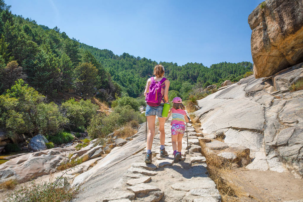 from behind daughter and mother hiking on a stones trail in Camo - 写真・画像