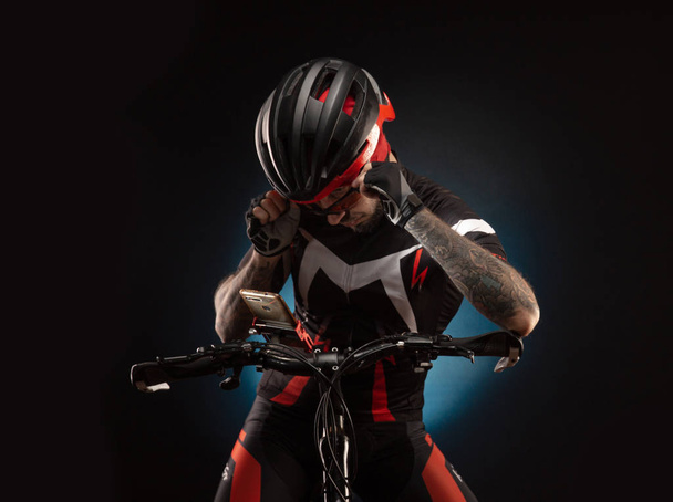 Парень в велосипедном шлеме смотрит в телефон.
 - Фото, изображение