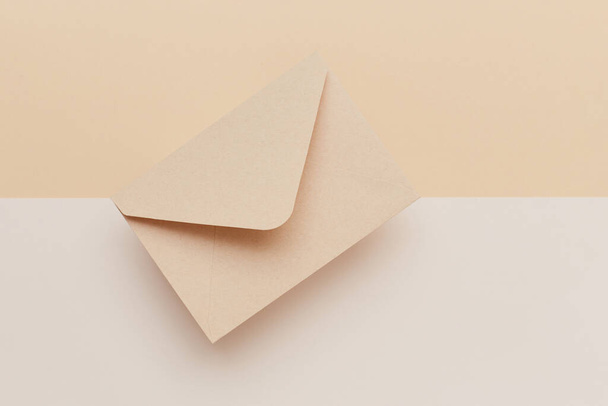 Biege envelop op de biege dubbel gekleurde achtergrond. Postconcept - Foto, afbeelding