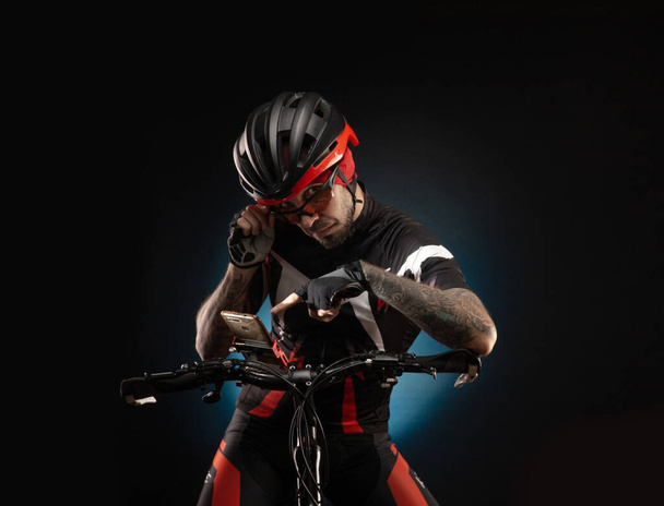 guy-cyclist v cyklistické helmě se podívá na telefon Navigator - Fotografie, Obrázek