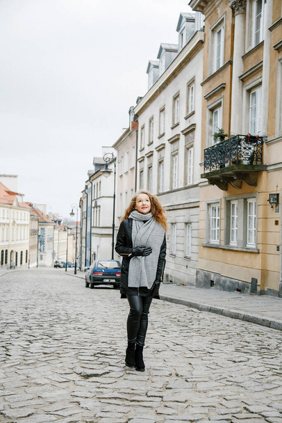 travel the old city. a young woman travels. market square in warsaw. curly girl walks through the streets of the city. - Foto, Bild