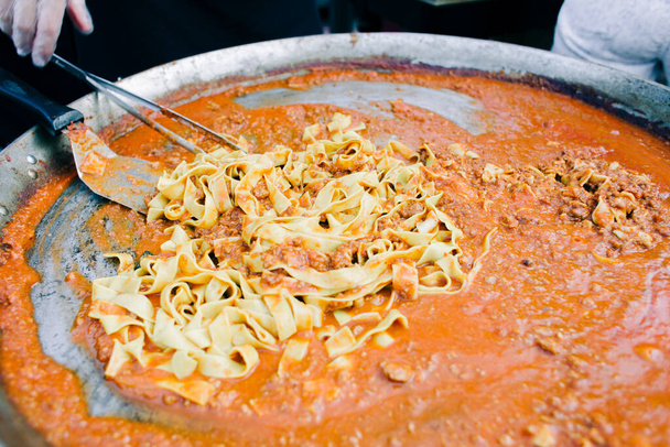 νόστιμα ζυμαρικά Bolognese μαγειρεμένα σε ένα μεγάλο τηγάνι, street food - Φωτογραφία, εικόνα