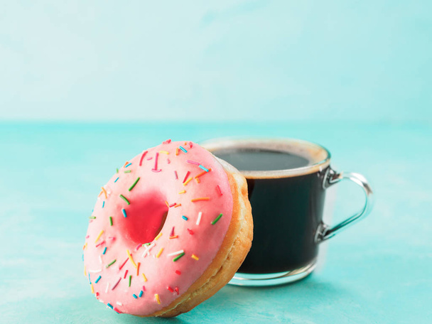 Pink donut and coffee on blue concrete background with copy space. Glazed doughnut and coffee cup with copyspace - Photo, Image