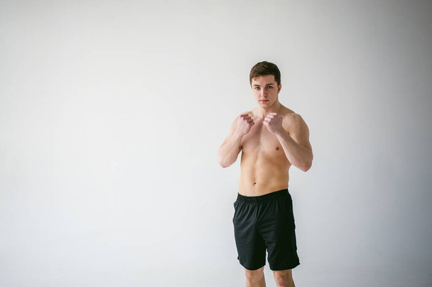 young sexy handsome men of strong Athlete's body with bare torso, Dressed black sports shorts, portrait of studio of light-skinned strong man standing in fighting stance, straining powerful hands - Photo, Image