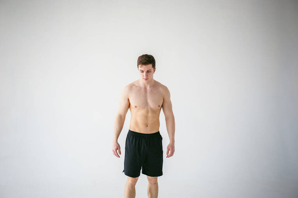 portrait young sexy handsome man of strong Athlete's body with bare torso, Dressed in a black sports shorts, Posing on white studio background - Photo, Image