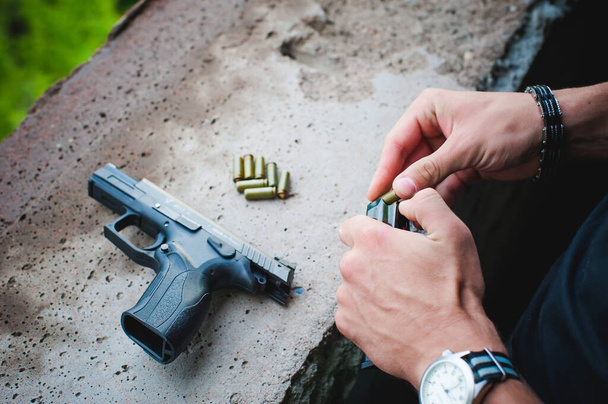 Man charges clip of pistol with bullets. Photo hands of paramilitary, reloading weapons. Preparation for shooting - Fotoğraf, Görsel