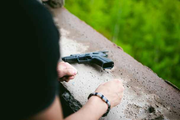 Mann erlegt Pistole mit Kugeln auf Hände von Paramilitärs beim Nachladen von Waffen. Vorbereitung auf die Dreharbeiten - Foto, Bild