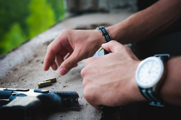 Mann erlegt Pistole mit Kugeln auf Hände von Paramilitärs beim Nachladen von Waffen. Vorbereitung auf die Dreharbeiten - Foto, Bild