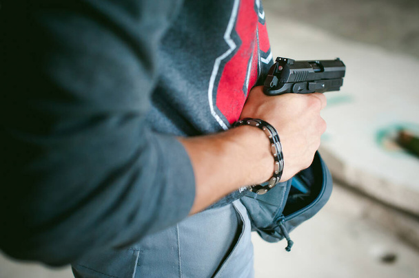 man pulls a gun out of his bag, holding it in his hand - Foto, Bild