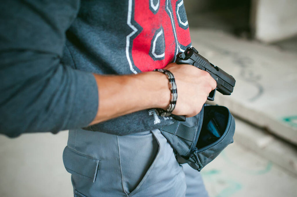 man pulls a gun out of his bag, holding it in his hand - Foto, immagini