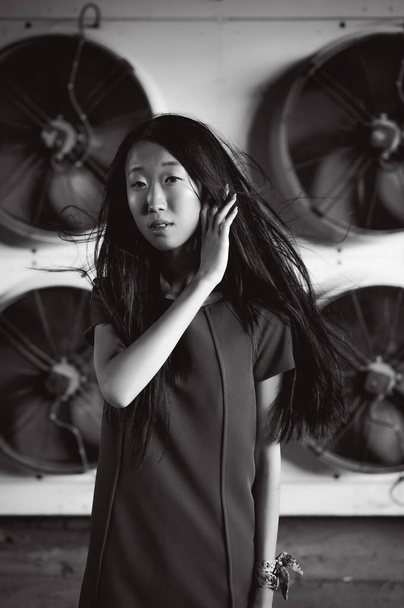 Young beautiful asian woman, on the background of industrial air conditioning system fans. Portrait of a girl with flying hair - Fotoğraf, Görsel