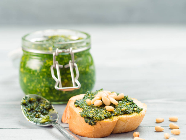 Close up view of baguette bread with fresh basil pesto sauce on gray wooden table. Copy space. - Photo, image