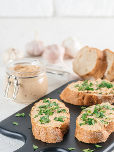 Close up view of slice bread with homemade turkey pate and fresh green parsley on black kutting board over white concrete background, Copy space. - Foto, immagini