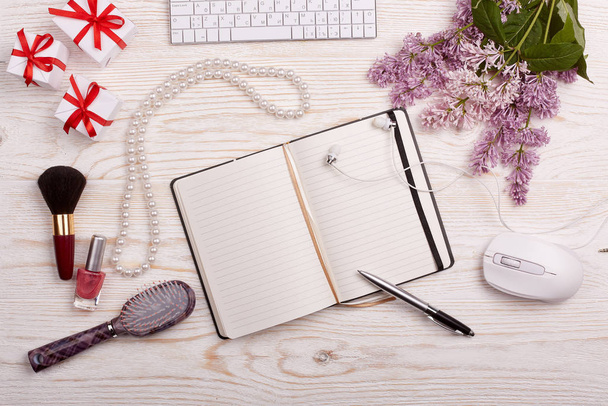 Trendy woman's desk with blank notepad for text, computer keyboard and mouse, gifts, jewelry,cosmetics and lilac flowers on ligth wooden background. Top view. Mockup. - Fotoğraf, Görsel