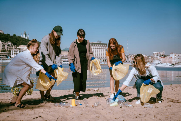 Gruppo di attivisti amici che raccolgono rifiuti di plastica sulla spiaggia. Conservazione dell'ambiente
. - Foto, immagini