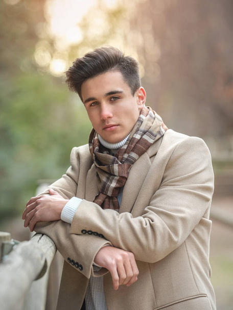 Portrait of a young guy on the street in a coat and scarf. - Fotó, kép