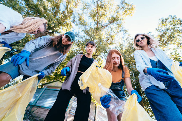 Grupo de ativistas amigos jogar um monte de lixo em um saco. Tiro de baixo para cima
 - Foto, Imagem